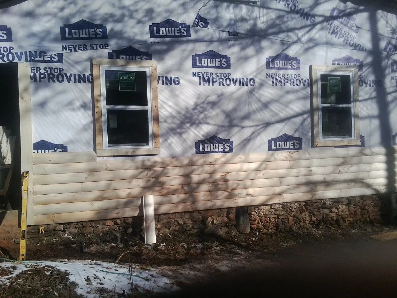 House wrap and new log siding going up on an exterior wall in Otis