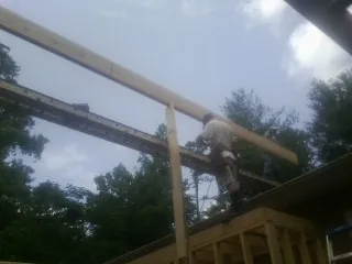 Carpenter setting a ridge beam over a new addition frame — Ice Dam Removal by Roofing Brothers in Otis