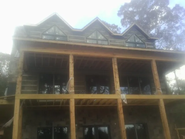 Dormers and porch framing on a large log home under construction — Roof Coating work by our crew in Otis