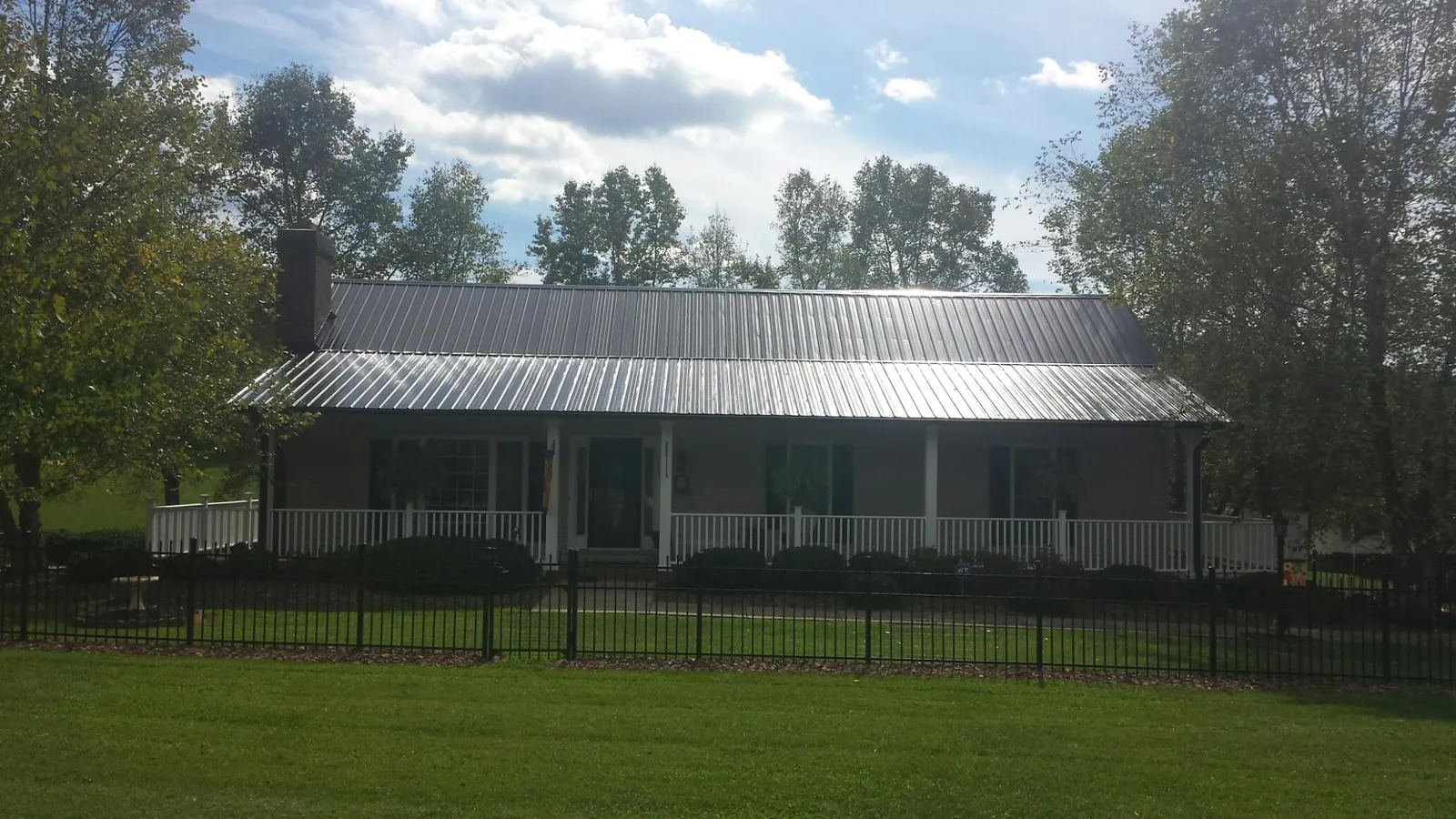 Gray metal roof on a brick ranch with a full width front porch — Gutter Guard Installation work by our crew in Otis